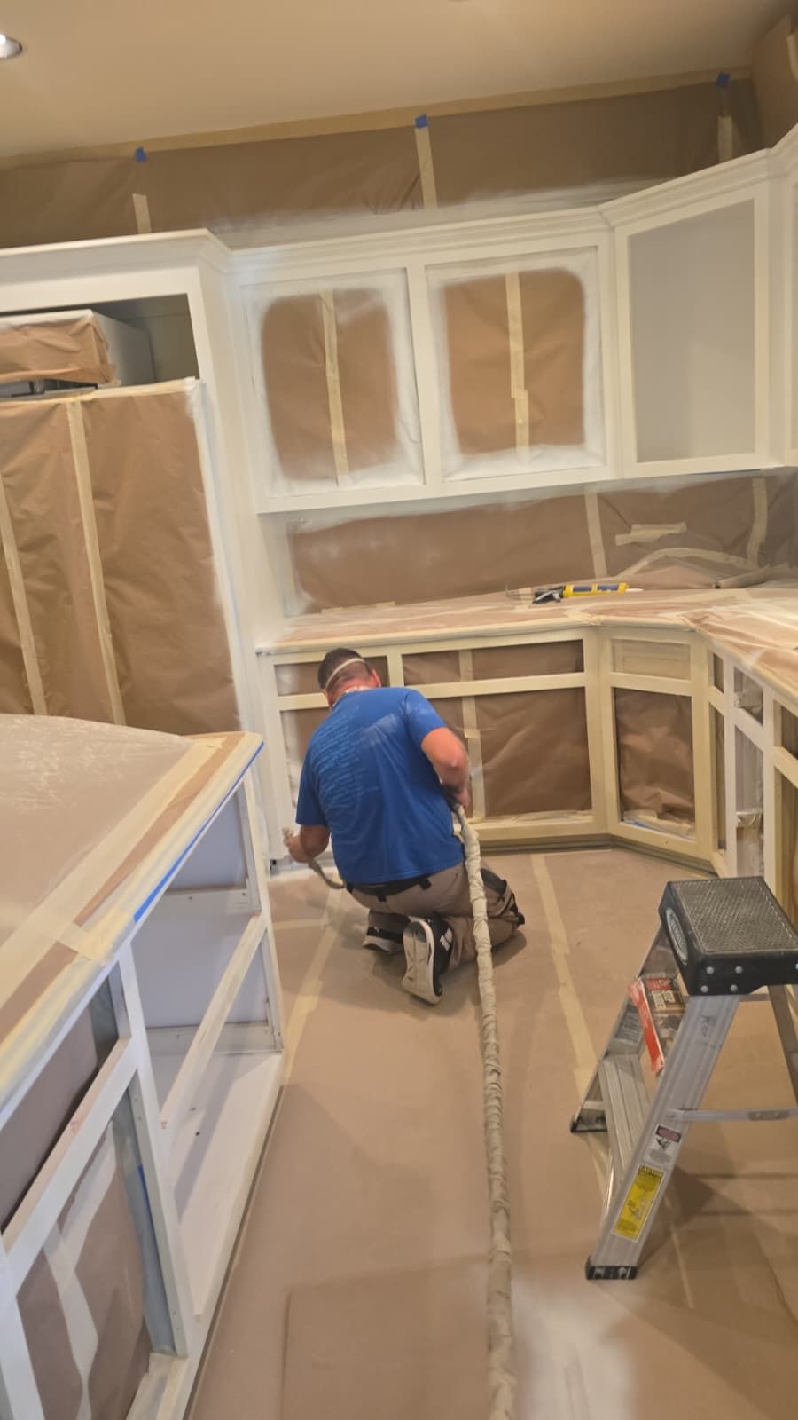 Craftsman spray-finishing the kitchen cabinets