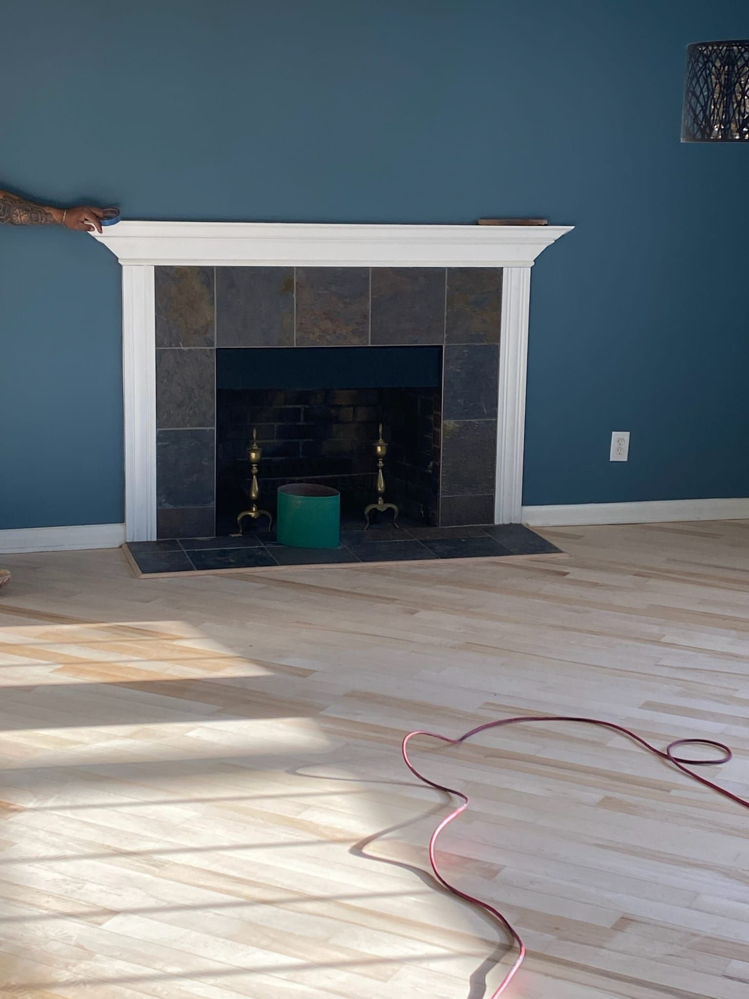 Finished white fireplace mantel with slate surround on a deep blue wall