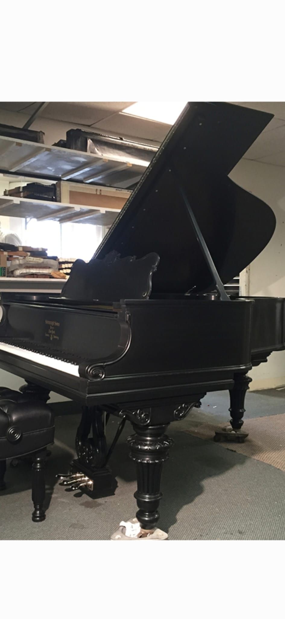 Restored black grand piano with ornate carved legs